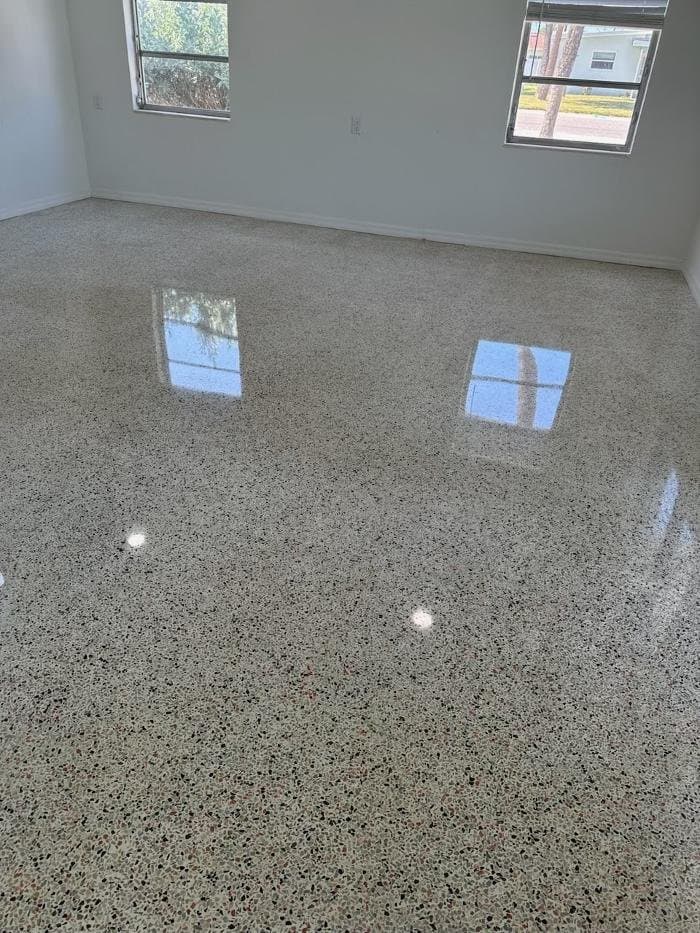 High-gloss polished terrazzo bedroom floor with black and pink chips reflecting two windows