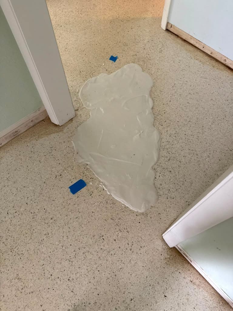 Poultice treatment applied to a terrazzo floor stain near the baseboard, Tampa Bay